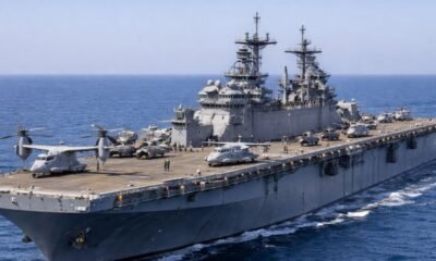 USS Iwo Jima amphibious assault ship underway at sea with helicopters and MV-22 Osprey aircraft on the flight deck.