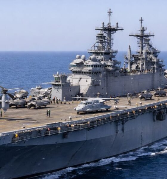 USS Iwo Jima amphibious assault ship underway at sea with helicopters and MV-22 Osprey aircraft on the flight deck.